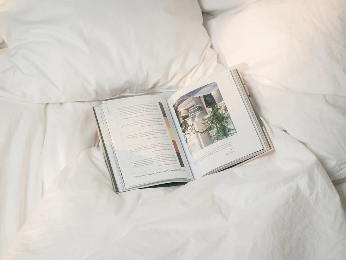 Närbild av en uppslagen bok liggandes i en obäddad säng